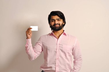 Yakışıklı, sakallı, resmi gömlekli bir iş adamı elinde kredi kartıyla kameraya bakıyor.