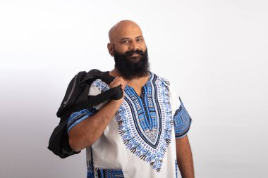 Hintli, orta yaşlı, Hawaii tişörtü giymiş ve elinde çanta tutan bir adam.