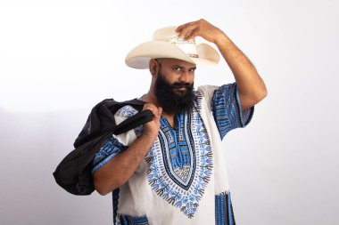 Hintli, orta yaşlı, kovboy şapkalı, Hawaii gömlekli ve çantalı bir adam.