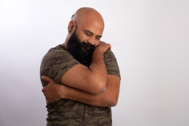 Orta yaşlı bir adam kendini kucaklıyor, omuzlarını tutuyor, yeni kazağında rahat hissediyor, romantik bir ruh hali var, sıcaklığı, rahatlığı ve sevgiyi hissetmeye ihtiyacı var, kendine bakım ve şefkat kavramı..