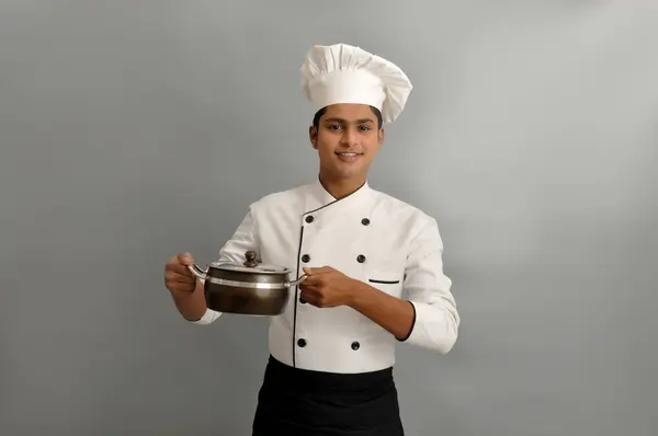 Indian chef smiling and holding pot in his hands