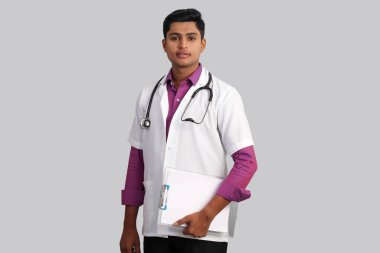 Boynunda steteskop olan genç, yakışıklı Hintli erkek doktor, beyaz arka planda izole bir klasör tutuyor. 