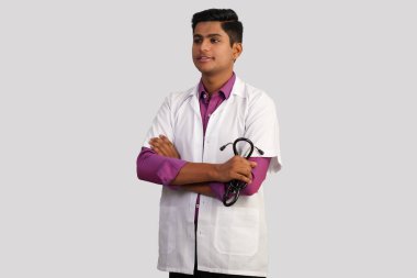Steteskoplu genç ve yakışıklı Hintli bir erkek doktorun portresi beyaz arka planda izole edilmiş çapraz kollar.