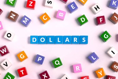 Harfli renkli küplerin üst görünümü, Pembe arka planda mavi kelimeden yapılmış DOLLARS sözcüğü