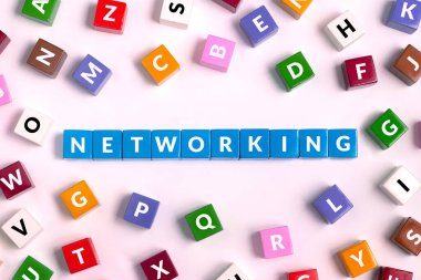 Harflerle dolu renkli küplerin üst görünümü, pembe arkaplanda maviden yapılmış NETworking kelimesi