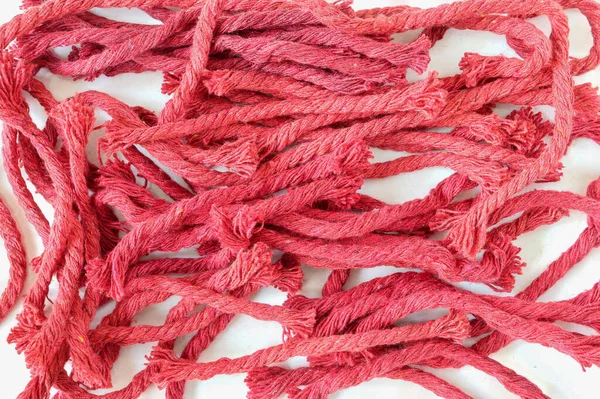 Red braided cotton rope. Pieces of red rope on a light background.