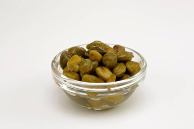 Cam bir kapta turşulu kapari. Beyaz arka planda yakın plan.