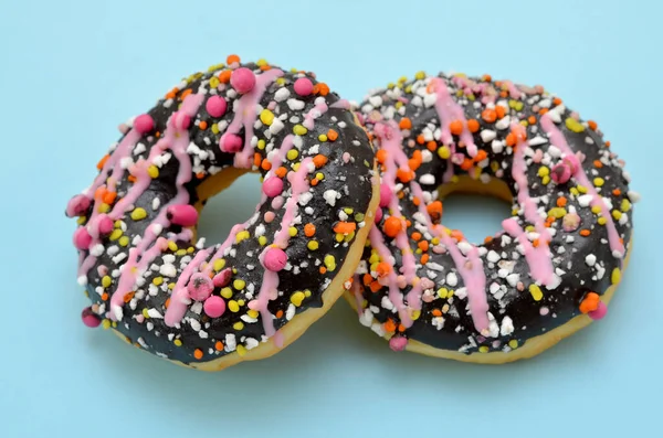 两个釉面甜甜圈 蓝色背景上有粉色洒水 — 图库照片