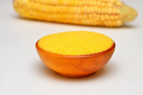 corn grits in a bowl and corn cobs in the background
