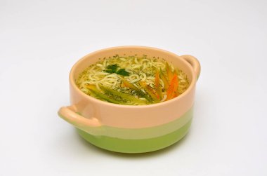 Erişteli Kore çorbası ve beyaz arka planda bir kasede sebze.