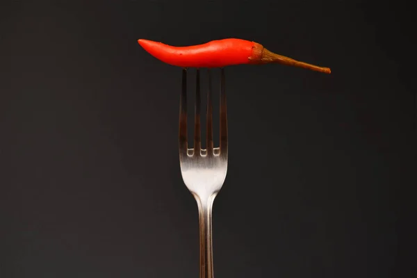 stock image hot chili peppers on a fork on a dark background close-up