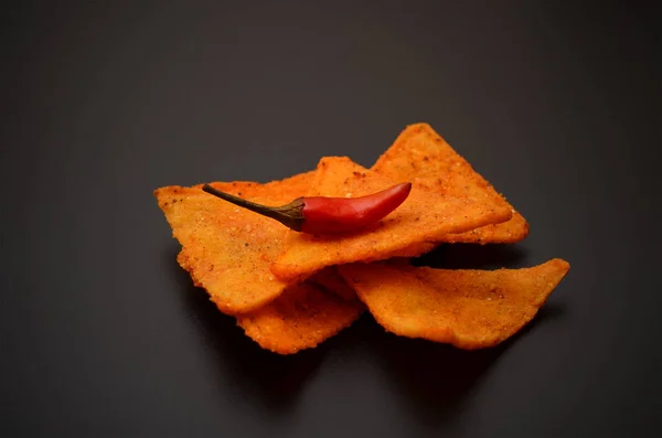spicy mexican chips and chili peppers on a black background