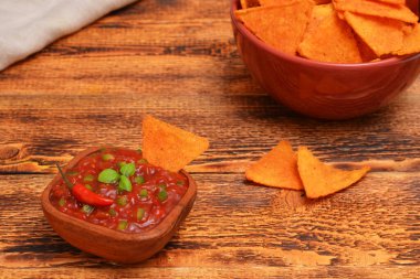 tomato salsa sauce in a bowl and corn chips nachos on the table