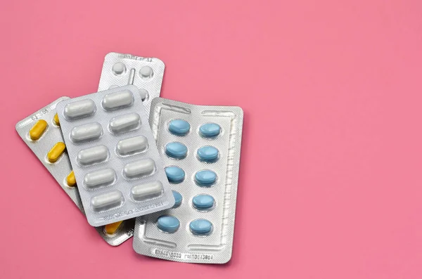 blisters of pills on a pink background, copy space