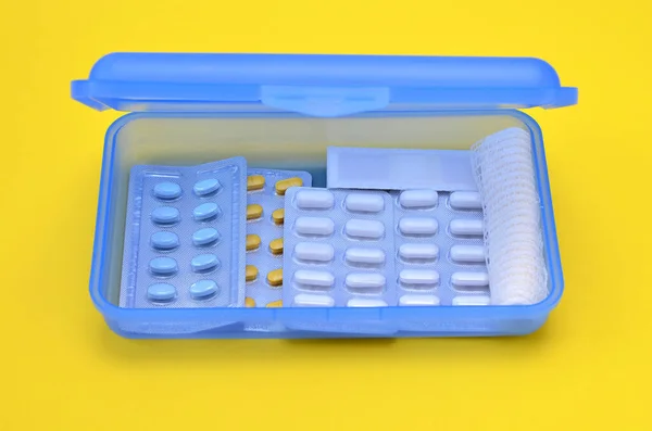 box with different medicines on yellow background