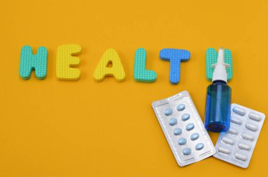 pills and the inscription health from the letters of the children's alphabet on yellow background