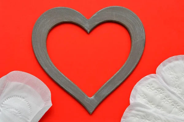 feminine hygiene pads and a heart frame on a red background