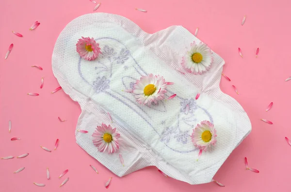 menstrual pad on a pink background and flowers close up