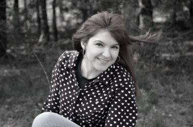 Güzel bir genç kadının siyah beyaz portresi dalgalı saçlarıyla doğanın arka planına karşı