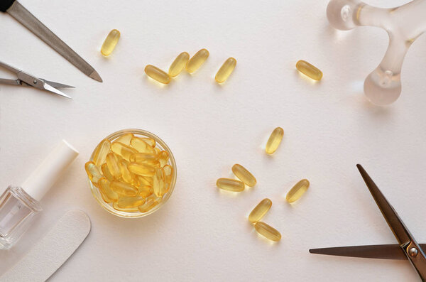 omega-3 capsules and tools for nail, skin and hair care, scissors, nail file and nail polish