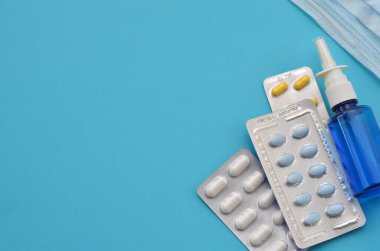 mavi arka planda farklı ilaçlar, haplar ve maske