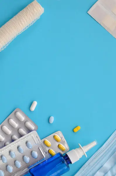 various medicines, mask, bandage and patch on a blue background