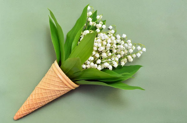 bouquet of lilies of the valley in a waffle cone on a green background, copy space