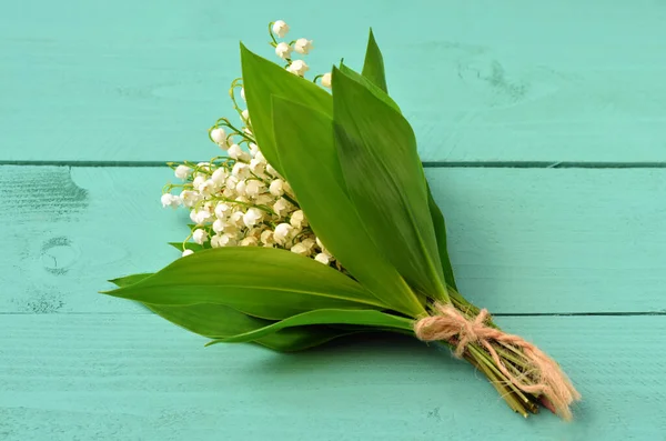 bouquet of lilies of the valley on a green wooden table close-up
