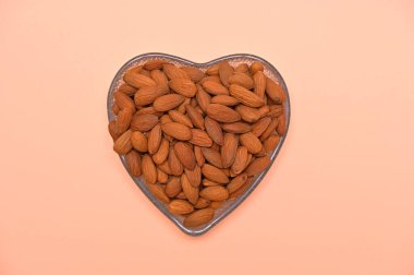 Şeftali arka planda kalp şeklinde bir kasede badem.