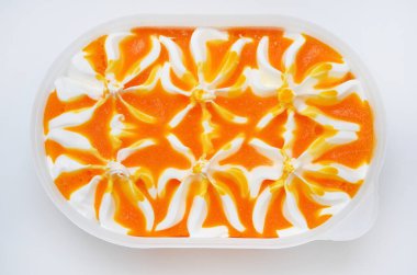 Beyaz arka planda plastik bir kutuda meyveli kremalı tatlı.