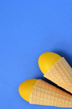 Sarı paskalya yumurtaları mavi arka planda waffle külahlarında, boşluğu kopyala