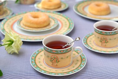 Bir fincan çay ve tatlı, şenlikli bir masada.