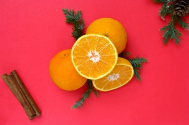 Kırmızı arka planda mandalina, çam iğnesi ve tarçın çubukları,