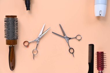 Kuaför aksesuarları, makas, tarak, saç fırçası ve hafif şeftali arkaplan üzerine sprey.