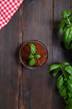 Tahta bir arka planda güneşte kurutulmuş domatesler ve yeşillikler.