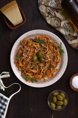 Tahta bir masada zeytinli İtalyan tagliolini makarna, koyu renkli natürmort