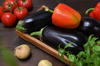 Taze yaz sebzeleri, patlıcanlar, tatlı biberler ve bitkilerle dolu ahşap kutu.