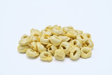 Beyaz arkaplanda çiğ tortellini yığını