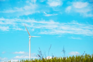 Rüzgar jeneratörü, rüzgar santrali, bulutlu mavi gökyüzüne karşı rüzgar türbini. Rüzgar enerjisini elektriğe dönüştürmek için bir cihaz. Yenilenebilir çevre dostu enerji kaynakları kavramı.