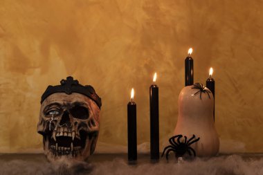 Cadılar Bayramı için turuncu kırmızı kasvetli arka plan. Siyah yanan mumlar, balkabağı, örümcekler, örümcek ağları ve kafatasları. Ruhanilik için aksesuarlar, kara büyü, falcılık..