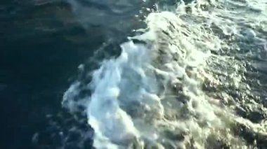 Koyu mavi deniz suyu üzerinde tekne hareketinden beyaz köpükler sıçrıyor ve sıçrıyor, yukarıdan yakın çekim görüntüsü, video yapıştırıcı, video geçişi, yatçılık romantik görünüm videosu