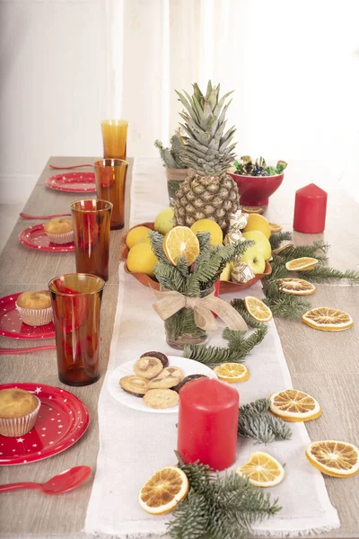 Christmas holiday table decorated with candles, Christmas tree branches, dried oranges, sweets and fruits,selective focus.Cozy house decorated for the holiday with handmade items.Christmas decoration.