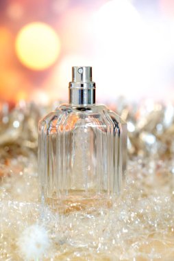 Şenlikli Noel parıltıları arasında bir şişe parfüm, zarif tonlarda güzel bulanık ışıkların arka planına karşı süslü bir süs. Parfümlerin Şenlikli Sunumu.
