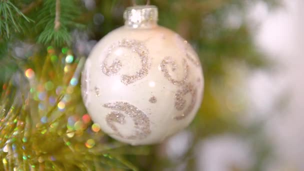 金银花做的漂亮的波克和一个旋转的玻璃圣诞球 在一棵天然圣诞树的枝条上有一个闪亮的图案 有选择性的聚焦 假日家居装修 — 图库视频影像