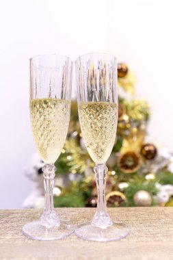 Şenlikli bir Noel ağacının arka planında şampanyalı kristal bardaklar, yakın plan. Yeni Yıl Arifesi.