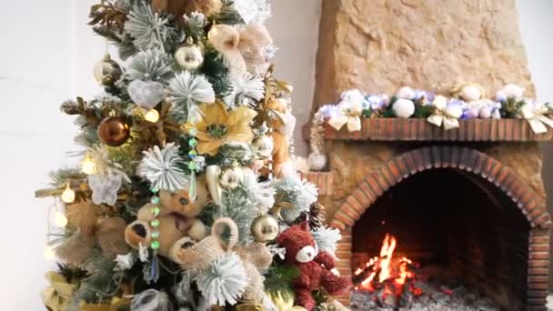 배경에 초점을 밖으로 벽난로에서 불타는 깜박이는 장난감 크리스마스 트리의 크리스마스 — 비디오