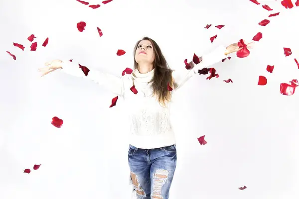 Woman C at falling rose petals, arms outstretched to the sides.Dreams for Valentine\'s Day.Concept of a happy woman.