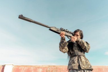 Portret üniformalı Afrikalı siyahi kadınlar, bir tüfeğin tetiğiyle optik bir görüşü hedefliyor, seçici bir odaklanma. Askeri harekat, adam atışı. Optik görüş yakın..