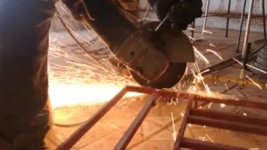 Uçan kıvılcımlı bir disk makinesiyle metali mekanik olarak kesmek. Bir işçinin elindeki dairesel alet metal bir yapıyı kesiyor.