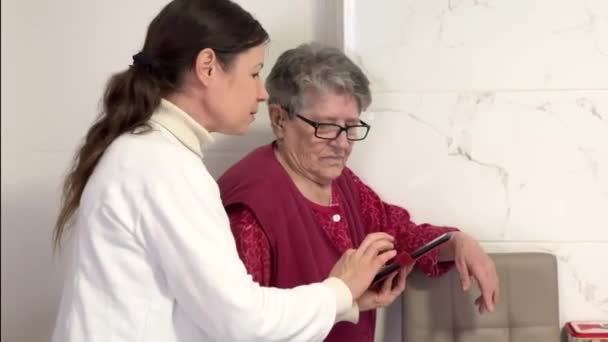 Женщины Среднего Возраста Объясняют Настройки Мобильного Телефона Пожилой Бабушке Изучение — стоковое видео
